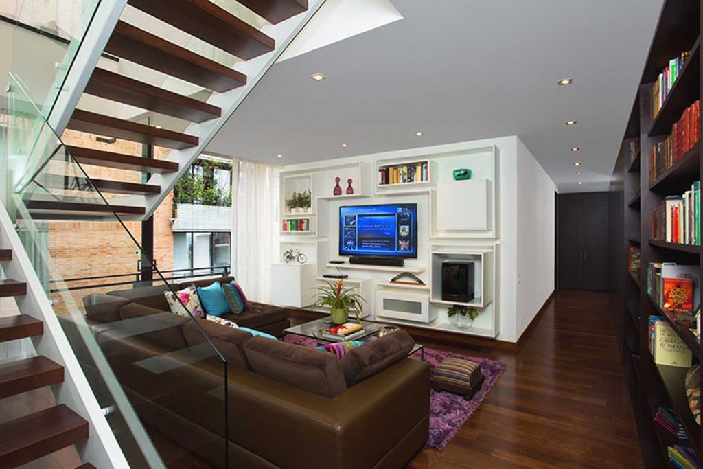 Para el estar Ríos diseñó el mueble de televisión y el sofá en L, en el que combinó cuero con tela del mismo tono y para crear contraste dispuso cojines de colores vivos. La tela del sofá y los cojines son de Denise Webb. Fotografía: Luis Fernando Ramos.