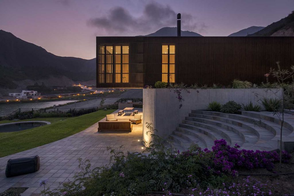 En la noche, el volumen superior acabado en madera se convierte en una caja de luz. Fotografía: Al atardecer el diseño de la iluminación transforma el aspecto de la casa  y le da  un carácter mágico. Fotografía: Renzo Rebagliati. 